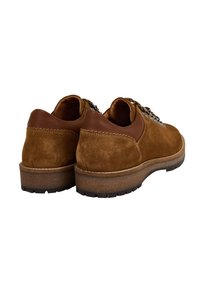 Un paio di scarpe da hiking in suede marrone con colli in pelle imbottiti, occhiali in metallo, lacci a motivo e suole in gomma spessa e texturizzata, viste da dietro.