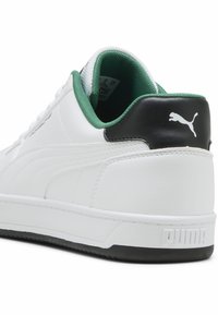 Valkoiset lenkkarit, joissa on nahkavarsi, vihreä vuori ja musta kantapää. Varusteena on teksturoitu pohja ja Puma-logo takana.