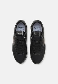 Paire de baskets Pepe Jeans noires avec des lacets noirs et un logo blanc sur la languette et les côtés, vues de dessus sur fond blanc.