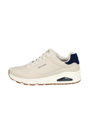 Zapatilla Skechers con parte superior de sintético beige, acento en azul marino en el talón, media suela blanca y un detalle de almohadilla de aire translúcida.