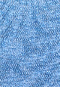 Primo piano di un tessuto di maglia blu che mostra dettagliate anse testurizzate e fili intrecciati in diverse tonalità di blu.