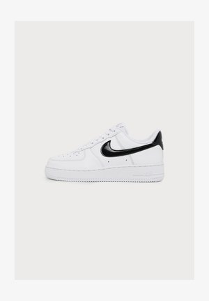 Bijela niska tenisica s crnim Nike logom i petnim jezičcem, bijelim vezicama i perforacijama na području prstiju.