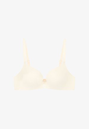 Crème-kleurige beha met gladde cups, verstelbare bandjes en een klein logo detail in het midden. Het materiaal lijkt zacht en naadloos.