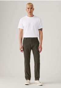 White short-sleeve T-shirt and dark green corduroy pants. The pants feature a slim fit and a smooth texture, paired with white sneakers.