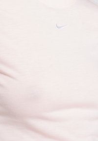 Ljusrosa Nike t-shirt med rund hals och subtil logotyp i en mörkare nyans. Slät textur med en åtsittande passform.