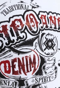 Witte stof met zwart en rood grafisch tekst; "DENIM" benadrukt in glanzend rood met ingewikkelde ontwerpen en patronen.