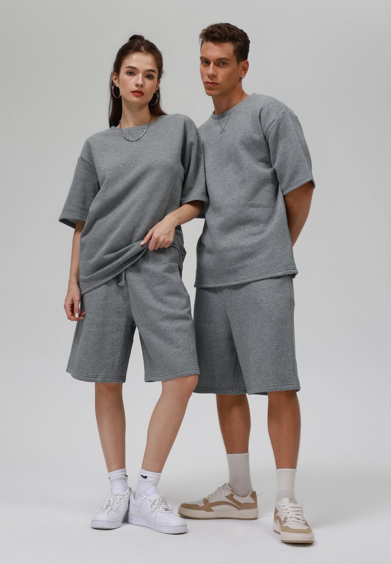 Grijze katoenmengsel oversized t-shirts en shorts met een ontspannen pasvorm en een zachte textuur, gecombineerd met witte en beige sneakers.