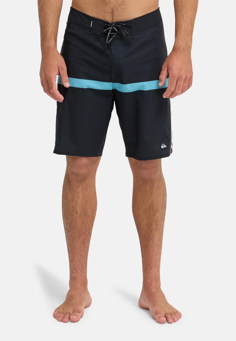 Shorts de bain noirs avec une bande horizontale bleu clair, dotés d'un tissu texturé et d'une fermeture à lacets à l'avant. Logo en bas à gauche.