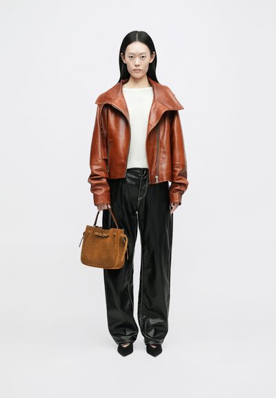 Ruda odinė striukė su plačiu apykakle, smėlinis megztinis, juodi blizgantys plačiakočiai kelnių, ir mažas rudų zomšinių rankinės. Juodi smailiakulniai batai.