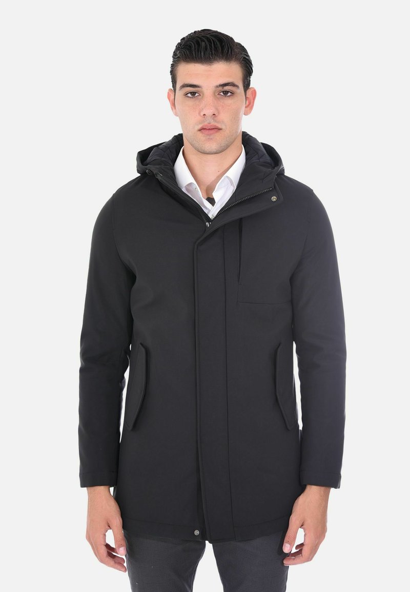 Parka nera con cappuccio, dotata di una chiusura frontale con zip, due tasche laterali e una tasca sul petto. Tessuto liscio con finitura opaca e design minimalista.