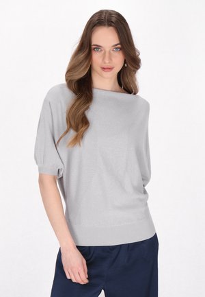 Lichtgrijze top met korte mouwen en een bootnek, gemaakt van textuurstof en met een ontspannen pasvorm. Gecombineerd met donkerblauwe broek.