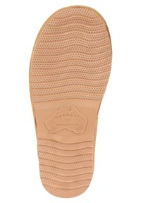 Rubberen zool met een gestructureerde oppervlakte, voorzien van een golfpatroon en driehoekige details. Gegraveerd logo met de tekst "WARMBAT AUSTRALIA" in het midden.