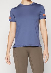 Kortärmad, blå träningströja med rund hals, med en orange detalj på vänster ärm och sprund i fållen.