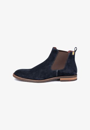 Marineblaues Wildleder-Chelsea-Boot mit braunen elastischen Seiteneinsätzen, hellbrauner Sohle und kontrastierenden Nähten; verfügt über eine Zuglasche an der Ferse.