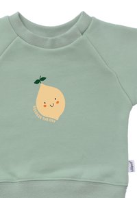 Grüner Sweatshirt mit geripptem Ausschnitt und Saum. Mit einem Zitronenmotiv und dem Text "Squeeze the Day" in Orange. Weiches Material.