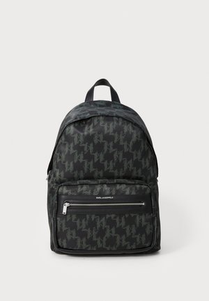 Black backpack with a houndstooth pattern in dark green. Features a top handle and a zippered front pocket with silver hardware.