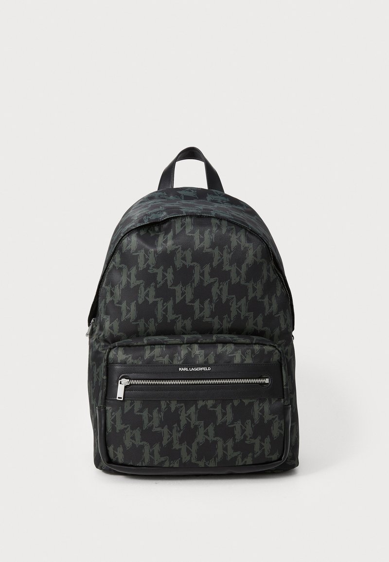 Black backpack with a houndstooth pattern in dark green. Features a top handle and a zippered front pocket with silver hardware.