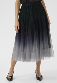 Čierna tylová sukňa s ombré efektom, zdobená rozptýlenými trblietkami a so vstavaným pásom. Nosená s metodicky špicatými čiernymi lodičkami.
