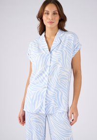 Ensemble de pyjama bleu clair avec un motif de zèbre. Haut à manches courtes avec boutons et pantalon assorti ornés de rayures blanches. Texture de tissu lisse.