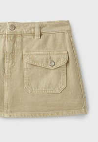 Mini-jupe en denim beige avec passants de ceinture, poche avant à rabat sécurisée par un bouton métallique et un bouton métallique à la taille.