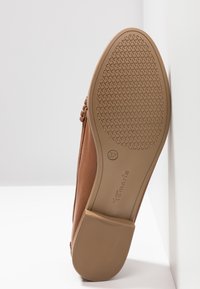 Semelle de chaussure plate marron avec motif texturé antidérapant, taille 37, et nom de la marque Tamaris embossé sur la semelle.