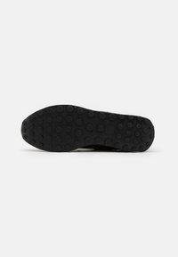 Semelle de chaussure en caoutchouc noir avec motif de semelle hexagonal, présentant de profondes rainures pour une traction optimale. Texture lisse, marquage minimal visible.