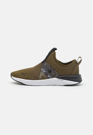 Zapatilla deportiva sin cordones de color verde oliva con suela negra y blanca, tira elástica cruzada, puntera de malla y lengüeta en el talón.