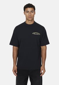 T-shirt nera in cotone con maniche corte e scollatura a girocollo. Presenta un logo dorato "GOODFORNOTHING" sul petto, vestibilità comoda.