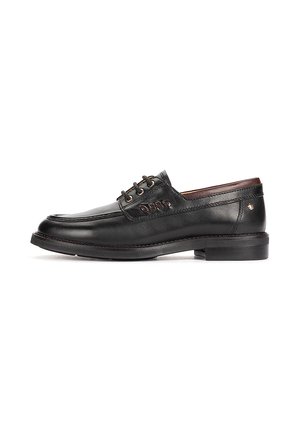 Zapato de vestir para hombre de cuero negro con cierre de cordones, tacón bajo y cortes decorativos en el lateral, mostrado sobre un fondo blanco.