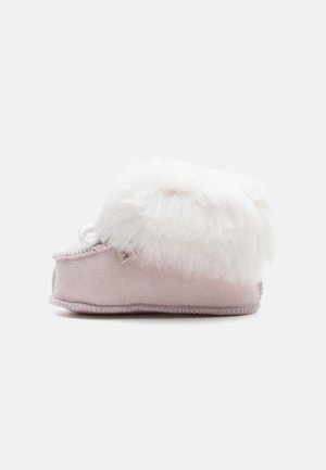 Weicher rosa Baby-Bootie mit weißem flauschigem Fellbesatz, Seitenansicht auf schlichtem hellem Hintergrund.