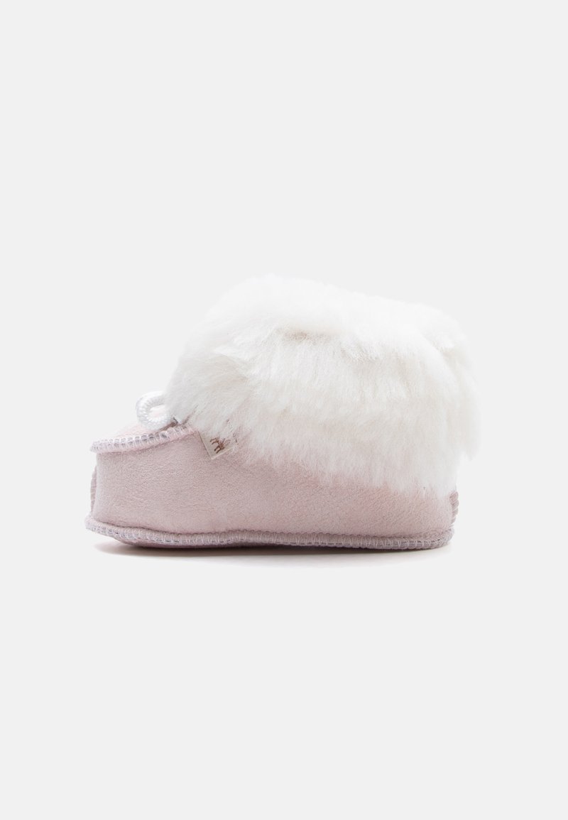 Chausson bébé rose doux avec bordure en fourrure blanche et duveteuse, vue latérale sur fond clair uni.