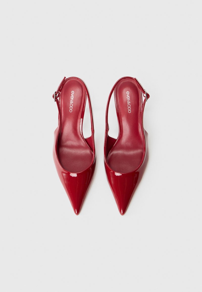 Tacchi slingback in vernice rossa, lucida, con punta appuntita e tacco sottile. Presentano una cinturino regolabile e suole interne imbottite.