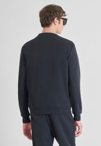 Sudadera de color navy con mangas largas y cuello redondo. Textura suave, puños y dobladillo acanalados, diseño minimalista y sin patrones ni logotipos visibles.