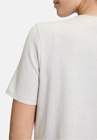Lichtgrijs T-shirt met korte mouwen, gemaakt van textuurstof met een subtiele glanseffect, voorzien van een klassieke ronde hals.