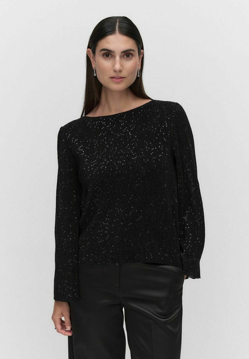 Sort ribbet sweater med metalliske pletter, bred bådformet halsudskæring, lange ærmer og slidser i siderne. Sættes sammen med sorte bukser for et sammenhængende look.