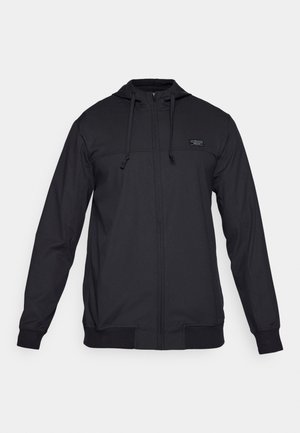 Felpa nera con zip realizzata in tessuto leggero. Presenta un cappuccio con coulisse, polsini e orlo a costine, e un piccolo logo sul petto.