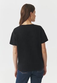 T-shirt nera a maniche corte realizzata in tessuto morbido, con una vestibilità comoda e un collo rotondo. Design semplice senza motivi o dettagli visibili.