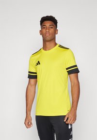 Yellow athletic shirt made from lightweight material, featuring black accented short sleeves and three black stripes on the shoulders.