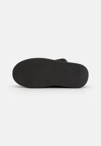 Svart gummisåle med en teksturert overflate, med et svakt hevet mønster for grep. Minimalistisk design med avrundede kanter.