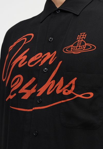 Μαύρο πουκάμισο με κουμπιά εμπρός και μεγάλο κόκκινο τύπωμα που αναγράφει "Ανοιχτά 24 ώρες" μαζί με ένα γραφικό λογότυπο. Διαθέτει τσέπη στο στήθος και απαλή υφή υφάσματος.