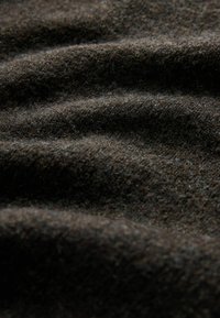 Dunkelbrauner Wollstoff mit einer weichen Textur, der sanfte Wellen und eine Mischung feiner Fasern zeigt und Tiefe sowie Wärme betont.