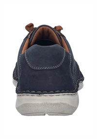 Granatowe zamszowe buty typu slip-on z przeszyciami, brązowe wewnętrzne wykończenie i teksturowana gumowa podeszwa. Gładkie wykończenie i casualowy styl.