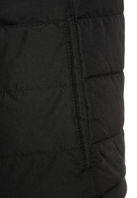 Sort puffer vest med quiltede sektioner, glat tekstur og skjulte sidelommer for funktionalitet. Minimalistisk design uden fremtrædende detaljer.