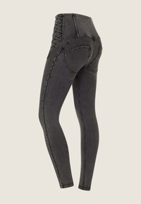 Mustat korkeat farkuleggingsit, joissa on tekstuuroitu sivupaneeli ja ristikkäin nauhat yksityiskohtana, ja kapeat lahkeet.