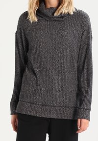 Šedý, texturovaný rolák se žebrovaným vzorem a dlouhými rukávy, s volným střihem a délkou, která sahá pod boky.