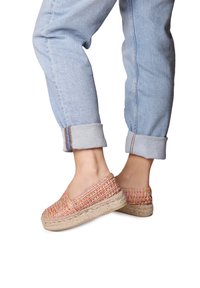 Scarpe espadrillas intrecciate in rosa e beige con suola in juta, indossate con jeans in denim azzurro chiaro con risvolto.