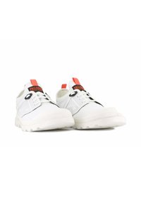 Weiße Sportschuhe mit einer strukturierten Gummisohle, Netzpaneelen und schwarzen Akzenten, ausgestattet mit einem roten Ziehband und einer markierten Zunge.