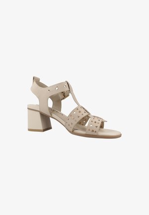 Sandalia beige con puntera abierta, tacón ancho, tira en el tobillo y tachuelas metálicas decorativas en varias tiras.