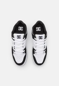 DC sneakers with a white leather and black suede upper. Features perforated toe box, flat white laces, and logo on tongue. Classic low-top design.