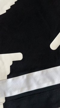 Tecido de camisola de desporto em preto e branco com uma risca de malha branca e um design gráfico parcial branco em material de malha preta.